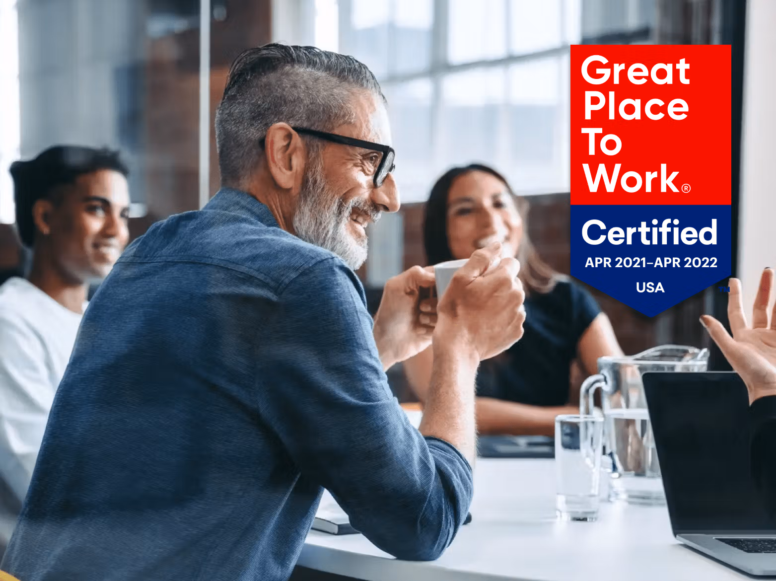 Workers collaborating at a meeting while sitting at a table.