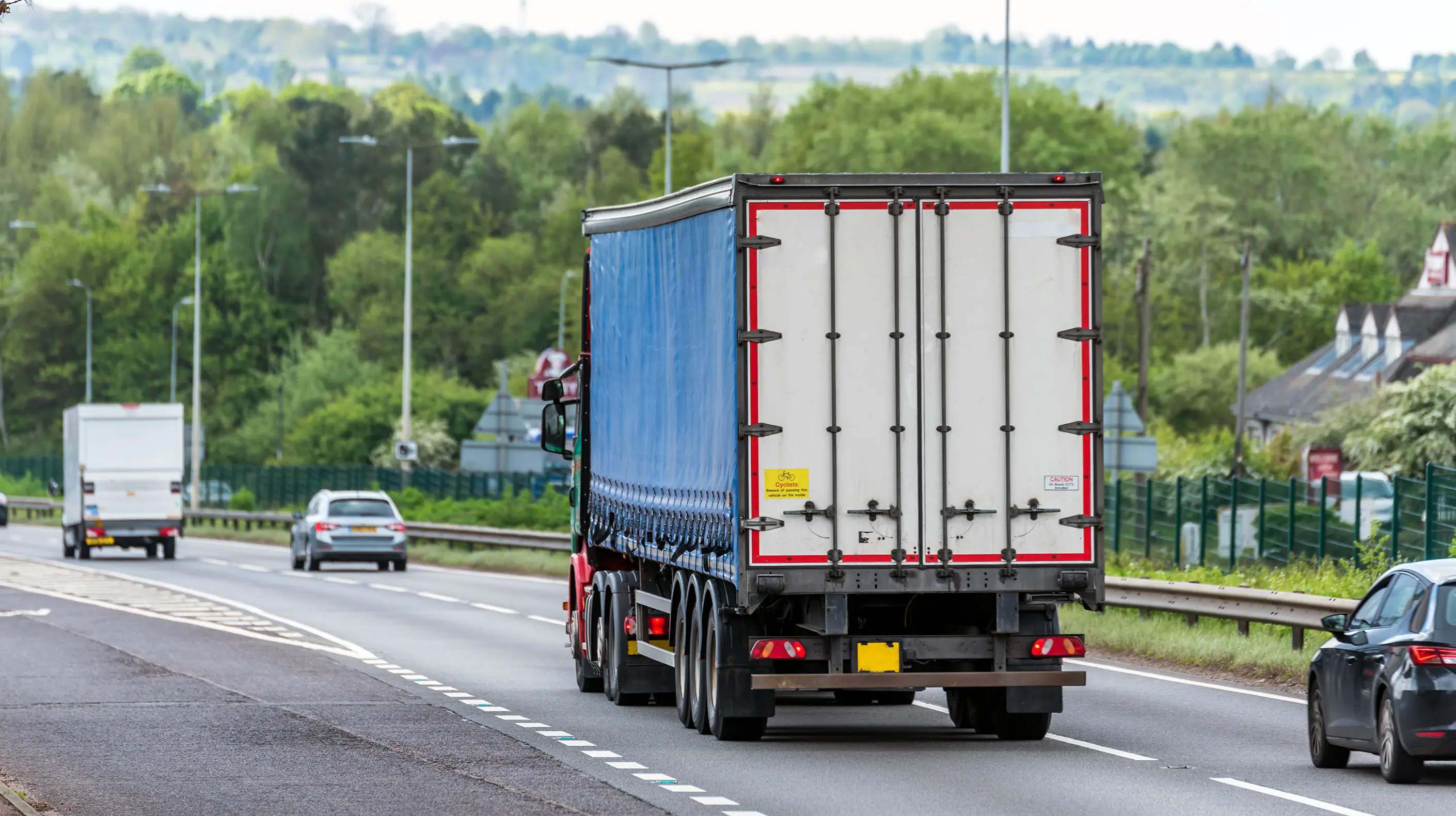 Photograph of the rear of a truck while it's driving down a road.