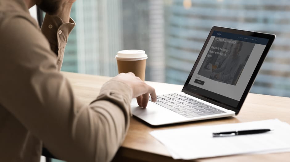 Office worker sitting at a desk while browsing through a support portal on their laptop.