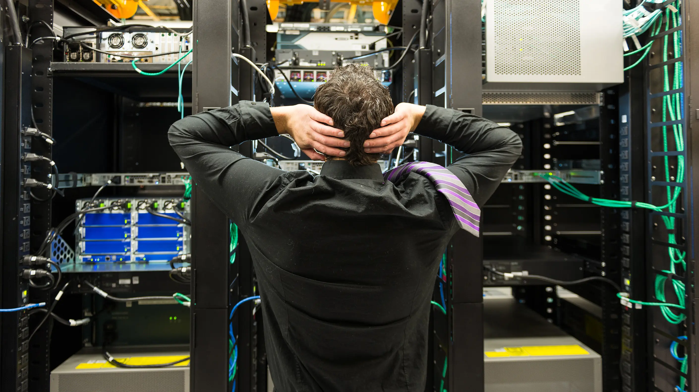 A stressed worker looking into a server room trying to figure out why there was a network failure.