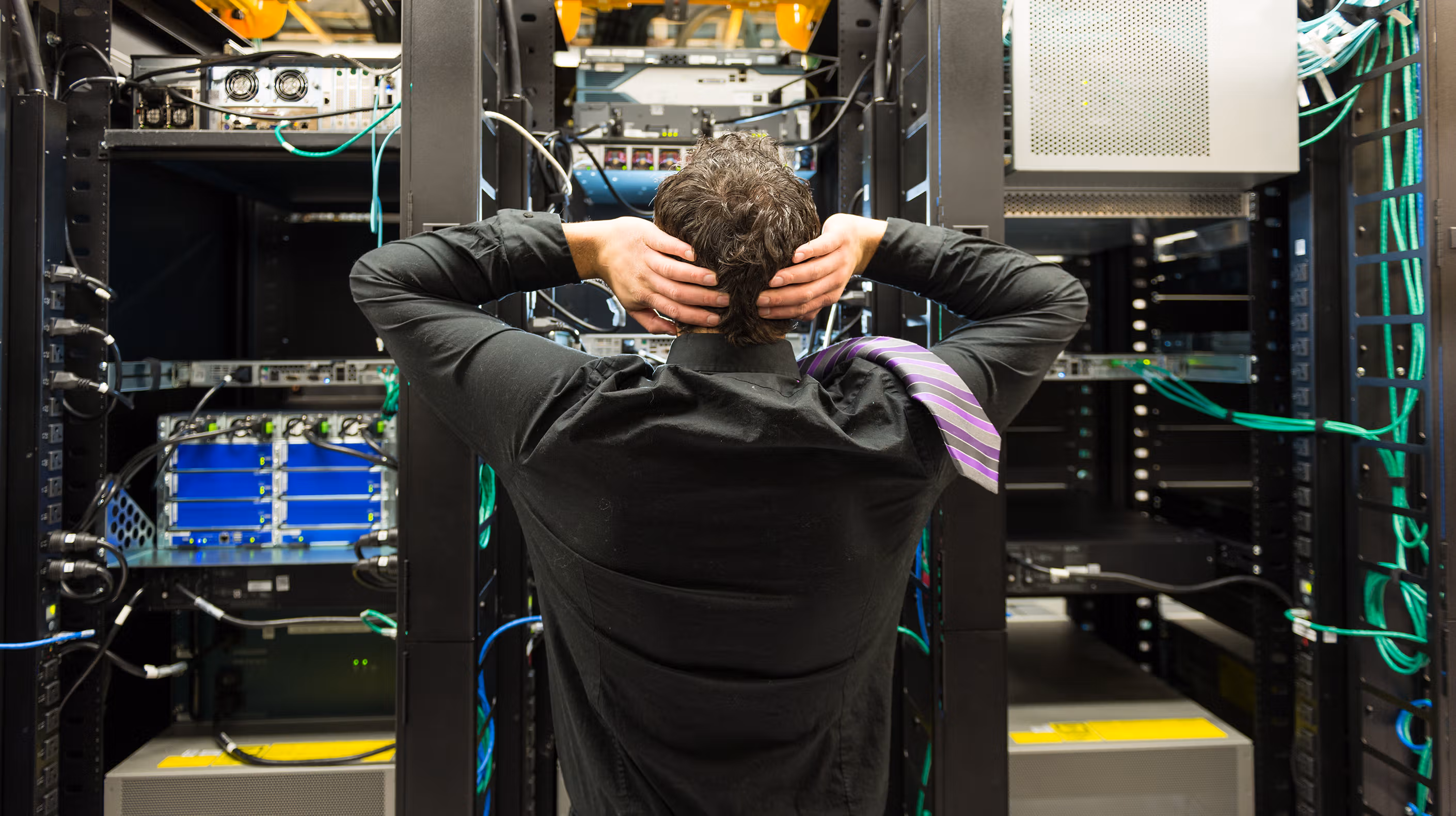 A stressed worker looking into a server room trying to figure out why there was a network failure.