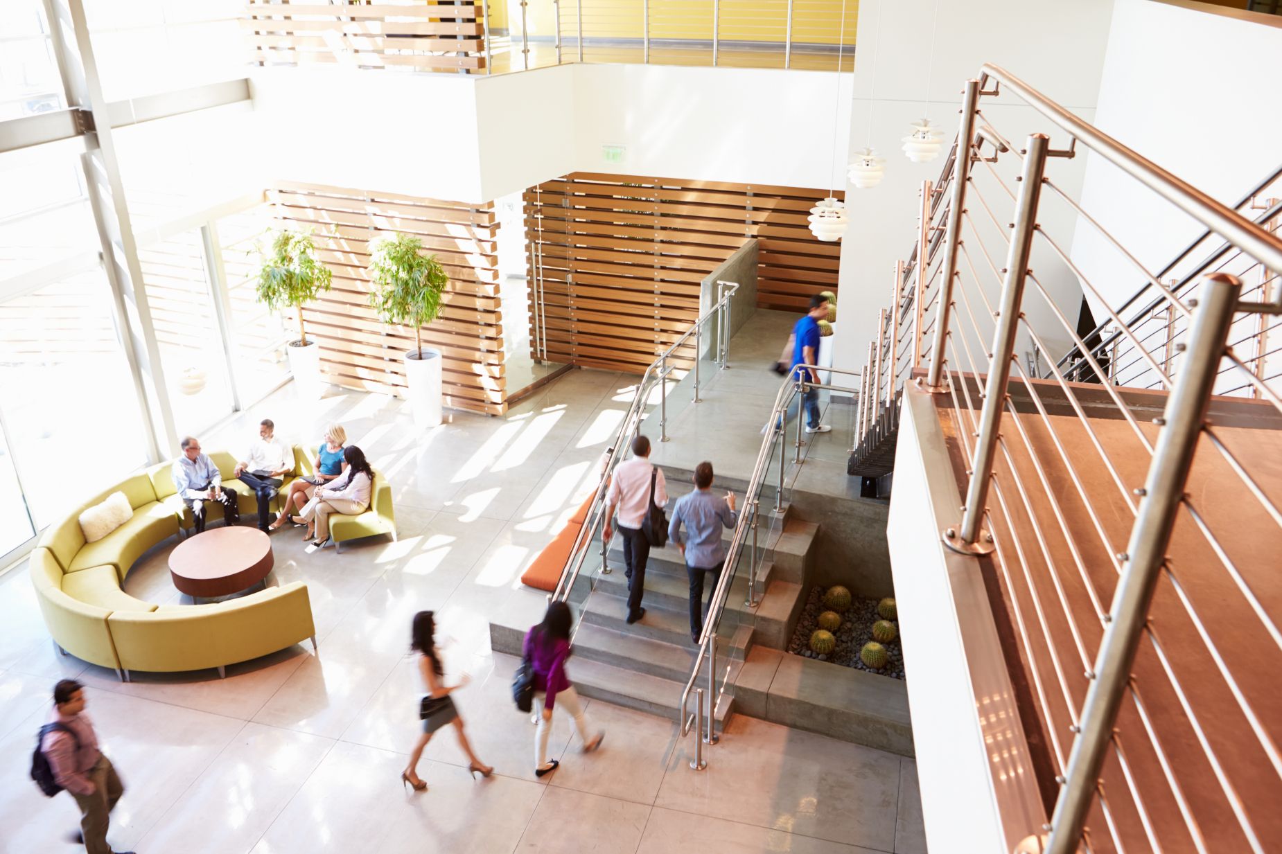 Picture of the inside of a building with multiple people walking up a set of stairs.