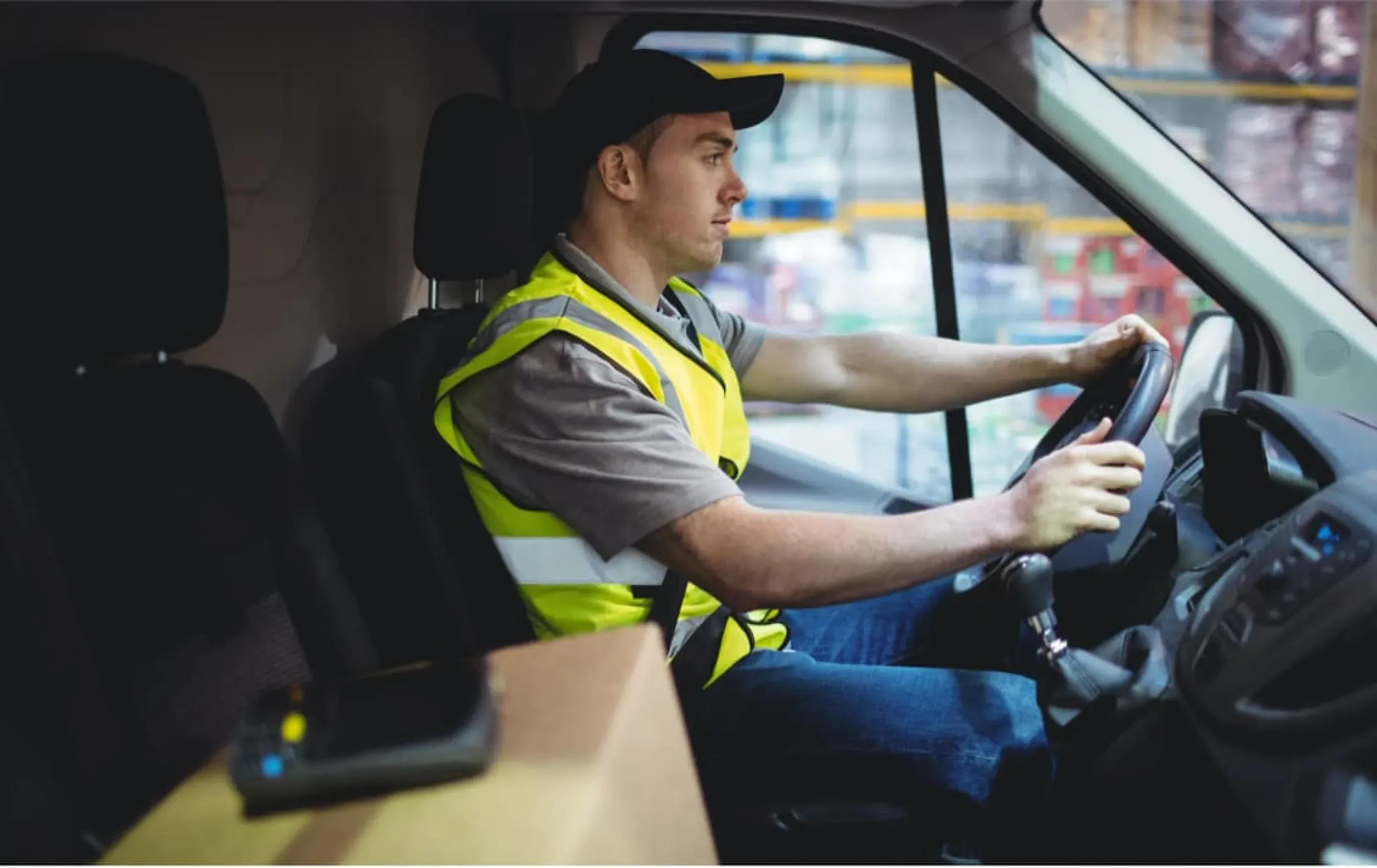 Sideview of a truck driver with their hands on the steering wheel.