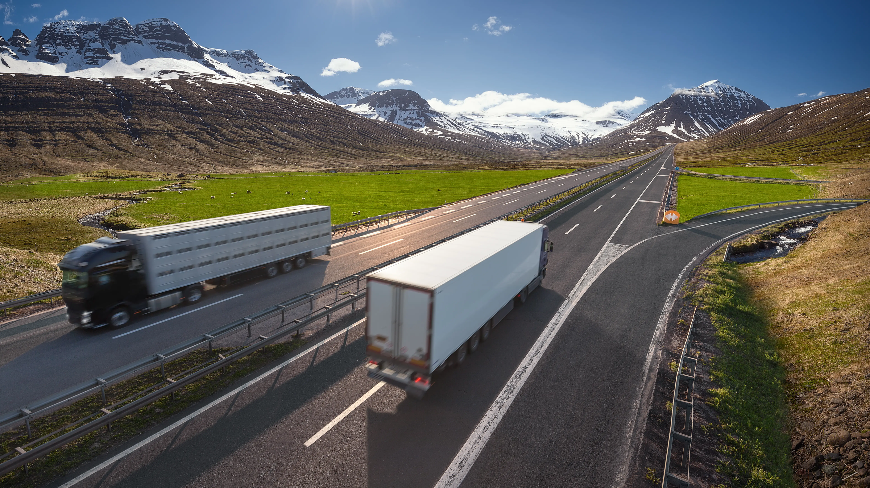 Photograph of a highway with two trucks driving past each other in separate lanes.