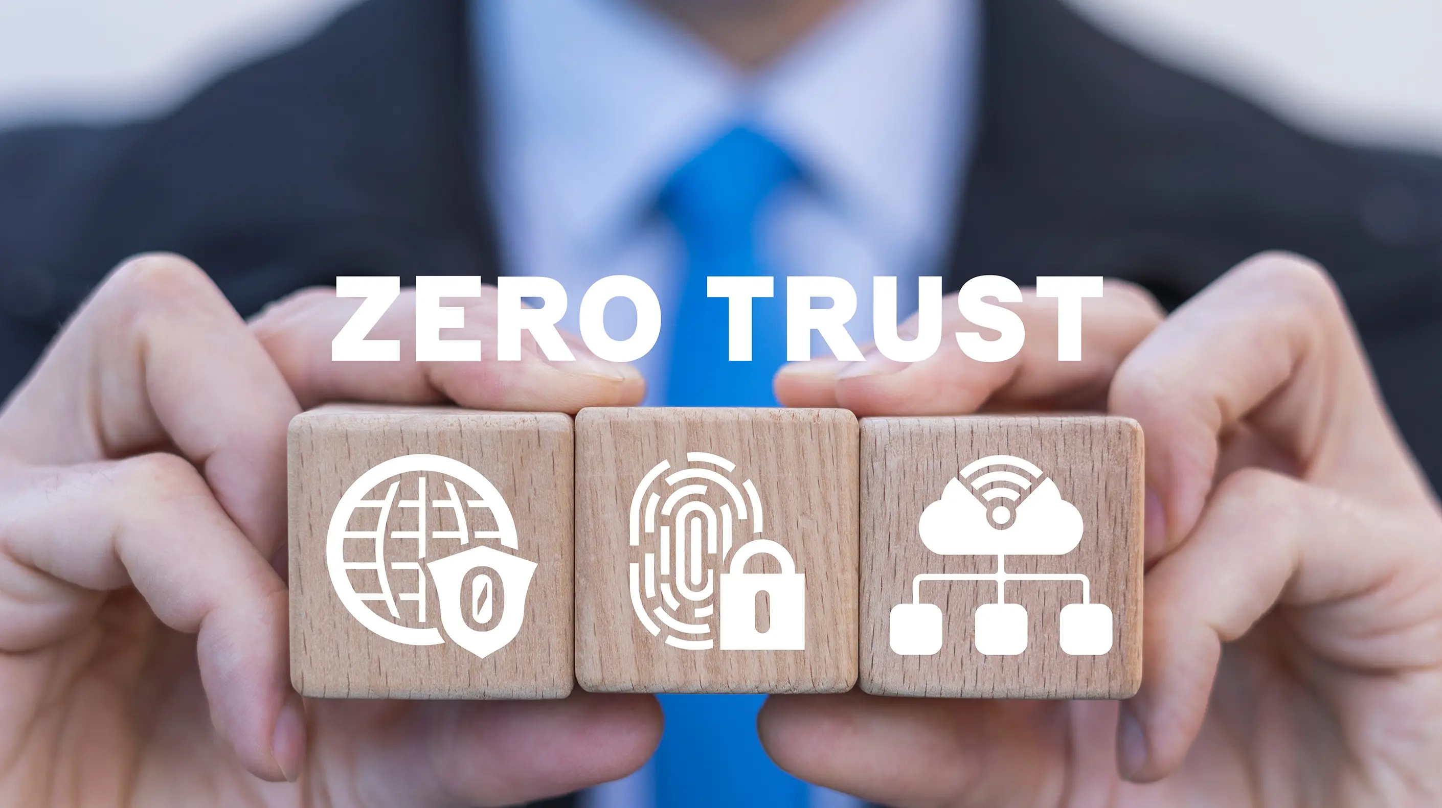 Business man holding up blocks showcasing a few icons that have to do with zero trust security.