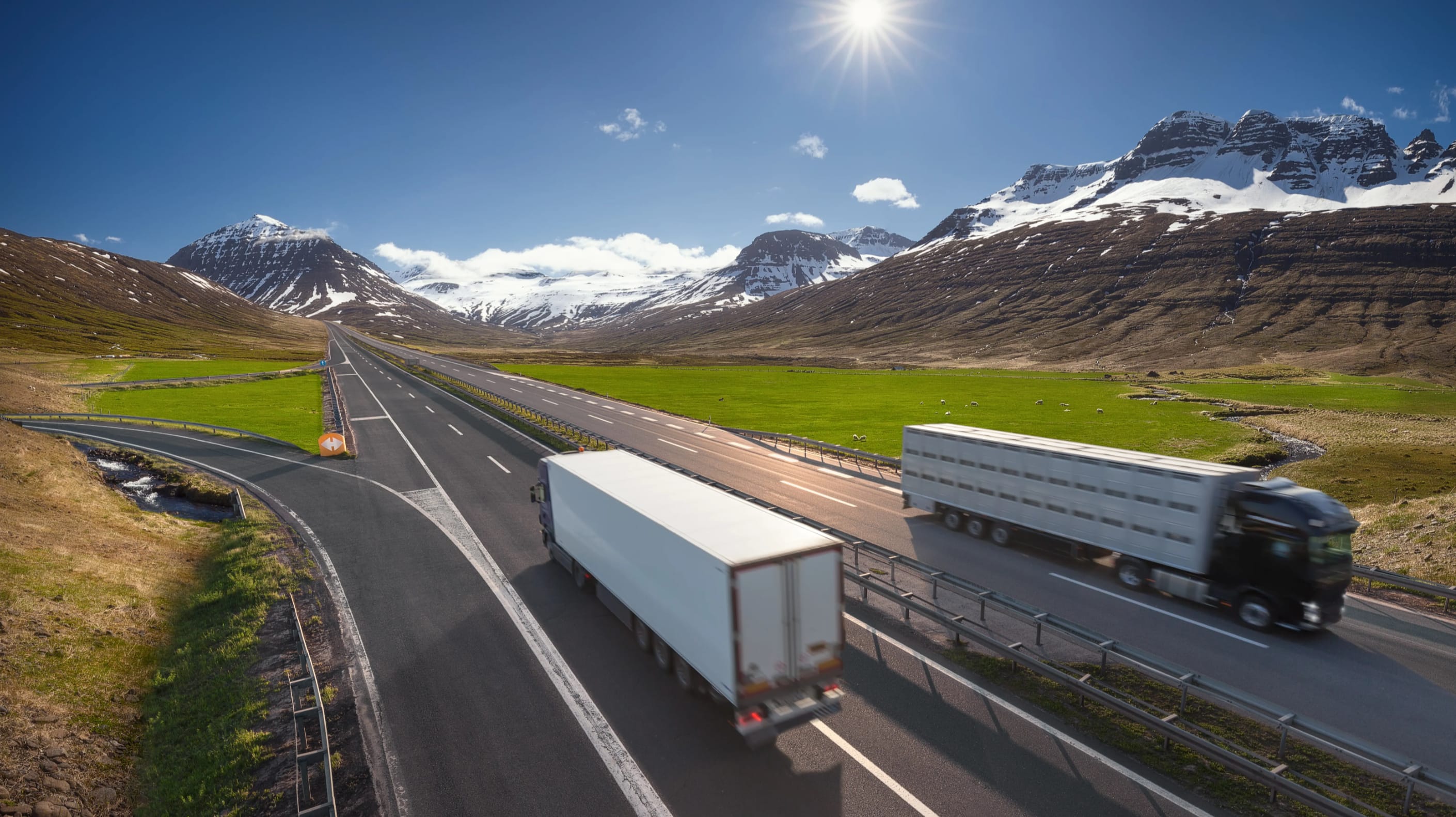 Photograph of a highway with two trucks driving past each other in separate lanes.