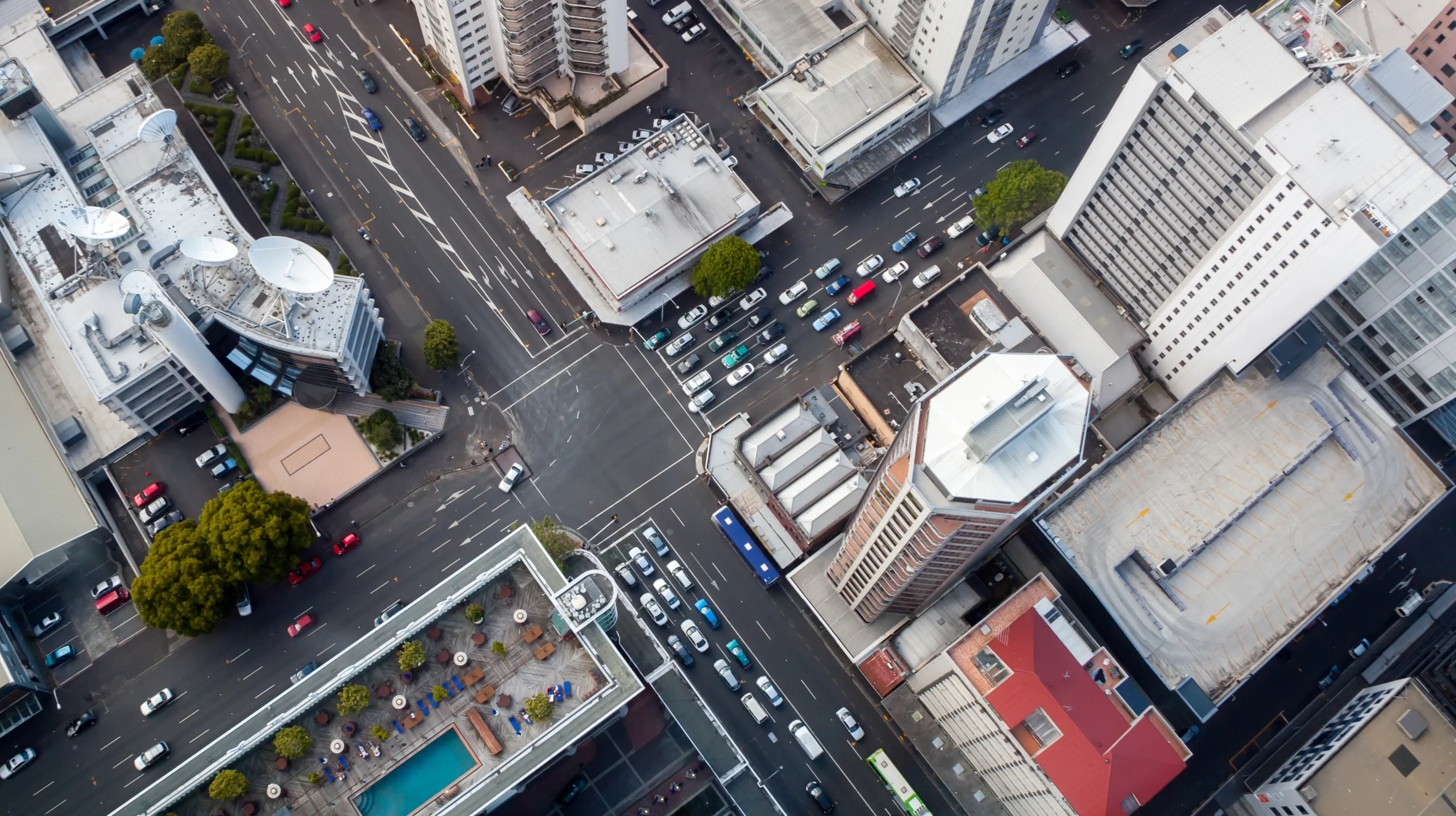 Skyview of a city's crossroad with cars waiting at a stoplight.