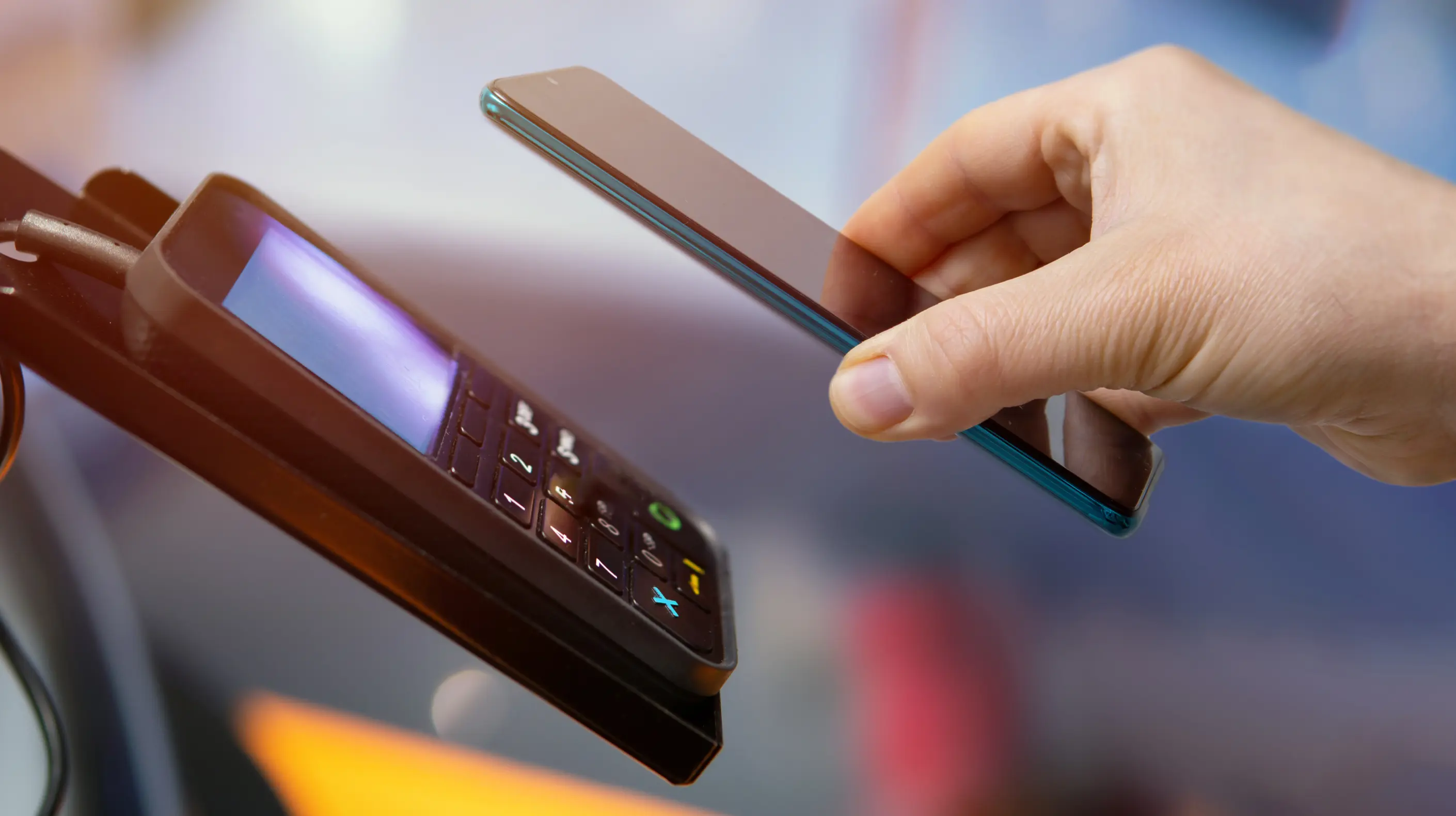 A mobile device being held over a credit card reader in a retail location.